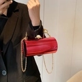 Red cylindrical acrylic evening bag with gold chain and large pearl clasp on model - Rose Red