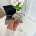 Silberne Acryl-Abendtasche in Muschelform mit Perlenkette in der Hand gehalten - Silber