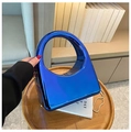 Close-up of electric blue acrylic clutch bag with a circular handle on a wooden tray - Blue