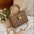 Vintage woven straw box bag with leather flap and gold chain strap on a soft background - Coffee