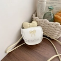 Mini bolso bandolera crema para niña con encaje y lazo sobre mesa de madera - Talla única / Blanco