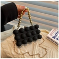 Detalle de bolso de fiesta negro con asa de cuentas doradas sobre fondo de punto suave - Negro