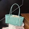 Detail of mint green woven shoulder bag featuring a cream drawstring liner on a wooden shelf - Green