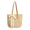 Detail der Basttasche mit Spitzen-Schleife und braunen Leder-Schulterriemen am Strand - Gebrochenes Weiß
