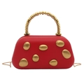Détail d'un sac de soirée rouge rigide avec des patchs dorés et une poignée perlée - Rouge