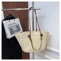 Close-up of woven straw tote bag featuring brown leather handles and textured craft - Off White