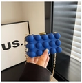 Detail of royal blue bubble textured evening bag with a gold chain strap and metal clasp - Blue