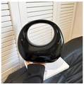 Close-up of a minimalist black patent leather round tote bag with glossy mirror finish - Black