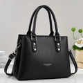 Large black leather tote bag with silver rivets and shoulder strap on white desk - Black