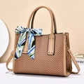 Close-up of V-shaped straw weave bag with leather handles and decorative scarf detail - Yellow