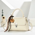 Détail d'un sac bandoulière tissé beige avec un pendentif bretzel en bois sur l'anse - Blanc Cassé