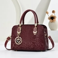 Close-up of wine red snake-textured leather handbag with heart pendant and gold hardware - Wine Red