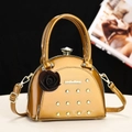 Glossy mustard semi-circle handbag with gold rivets and crystal clasp on a modern stand - Gold