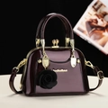 Détail du sac à main en cuir verni bordeaux avec garniture dorée et pendentif rose - Violet foncé