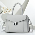 Detailed macro view of litchi textured leather handbag with metallic geometric lock - Gray