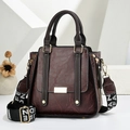 Brown leather women handbag with wide logo strap and retro textured finish on a white stand - Brown