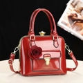 Elegant red patent leather handbag with 3D rose decor and gold hardware on a dark backdrop - Red