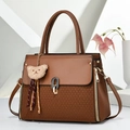Detail of warm brown leather tote featuring V-shaped woven texture and bear pendant - Khaki/Earth Yellow