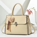 Detail of beige tote bag with cute plush bear charm and decorative woven tassels - Light Khaki