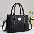 Close-up of black textured leather handbag with silver lock and fine stitching details - Black