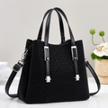 Borsa tote nera intrecciata minimalista con dettagli in argento su scrivania bianca - Nero
