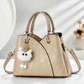 Elegante khakifarbene Henkeltasche mit Textur und Plüsch-Anhänger im minimalistischen Studio - Khaki
