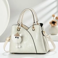 Detail der cremefarbenen Retro-Handtasche mit goldener Micky-Hardware und Plüsch-Anhänger - Cremeweiß
