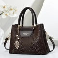 Sac à main marron foncé à motif serpent avec pendentif feuille sur support en marbre - Café