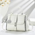 White faux crocodile leather handbag with silver lock and clover charm in soft sunlight - White