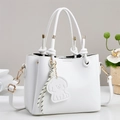 Close-up of white lychee leather handbag with knot handle and dog charm detail - White