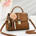 Detailed view of caramel brown crossbody bag with gold lock and plush pendant accessory - Brown