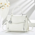White crocodile pattern handbag with silver hardware and orchid decor in soft lighting - White