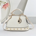 Detail der weißen Handtasche mit Schlangenmuster, goldene Nieten und Herz-Anhänger - Cremeweiß