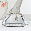 Detail der silbernen Handtasche mit Schlangenmuster, Goldnieten und Blumenherz-Anhänger - Silber