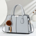 Borsa a mano minimalista grigio chiaro con ciondolo, presentata in una cornice artistica - Grigio