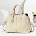 Detail der gewebten Stroh-Tasche mit Chevron-Struktur und Lederbesatz mit Metallanhänger - Cremeweiß