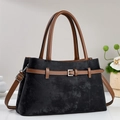 Detail view of black and brown tote bag with metal buckle and detachable shoulder strap - Black