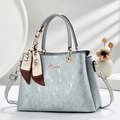 Close-up of light blue textured handbag with gold logo and printed silk scarf handle - Gray