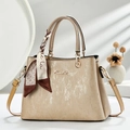 Detail einer eleganten champagnerfarbenen Handtasche mit Seidentuch und goldenem Logo - Khaki