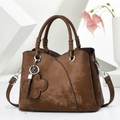 Détail du sac à main marron mat avec pendentif trèfle et bords ondulés - Café