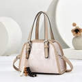 Detail of light pink pleated handbag featuring fashion text and beaded tassel detail - Pink