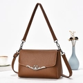 Close-up of brown pebbled leather texture and silver heart-shaped metal buckle on the bag - Brown