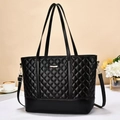 Primer plano detallado de un bolso tote negro acolchado con rombos y placa metálica de marca - Negro