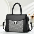 Detail of a chic trapezoid handbag with black and white woven texture and silver lock - Black