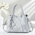 Elegante borsa grigio chiaro con trama trapuntata e ciondolo a quadrifoglio nella luce - Grigio