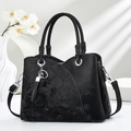 Detail of black quilted shoulder bag featuring silver hardware and a floral leather pendant - Black