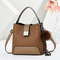 Détail du sac à main marron tissé avec fermoir doré et accessoire boule en peluche - Café