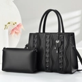 Set borsa tote in pelle nera con ciondolo a cuore e pochette in un ambiente minimalista - Nero