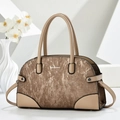 Detailed view of the textured bronze panel and beige leather handle of this stylish handbag - Coffee