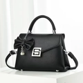 Elegant black pebble leather handbag with silver clasp and pearl bow charm detail - Black